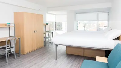 a bedroom with a large bed and a desk and a chair at Campus1 MTL Student Residence Downtown Montreal in Montréal