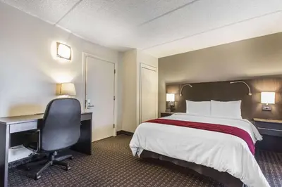 a hotel room with a bed and a desk and a chair at Hôtel Le Principal in Granby