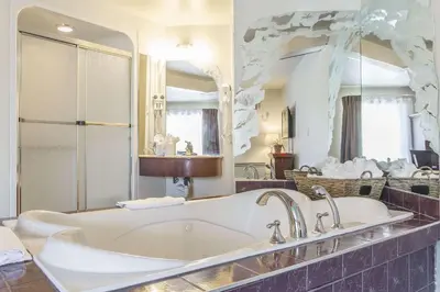 a bathroom with a tub and a large mirror at Hôtel Le Principal in Granby