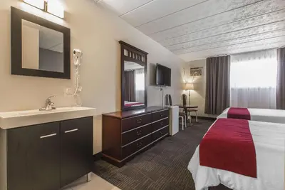 a hotel room with a bed and a sink at Hôtel Le Principal in Granby