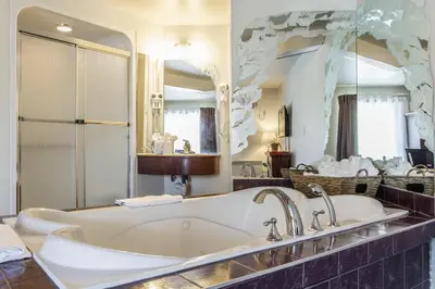 a bathroom with a tub and a large mirror at Hôtel Le Principal in Granby