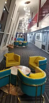 a lobby with yellow and blue chairs and a table at Baymont by Wyndham Montreal Airport in Dorval