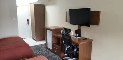 a hotel room with a desk with a television on it at Baymont by Wyndham Montreal Airport in Dorval