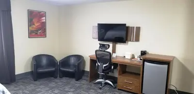 a room with a desk with a computer and chairs at Baymont by Wyndham Montreal Airport in Dorval