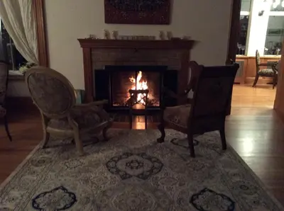 a living room with two chairs and a fireplace at Île de Garde B&B in Sherbrooke