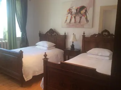 a bedroom with two beds and a painting on the wall at Île de Garde B&B in Sherbrooke