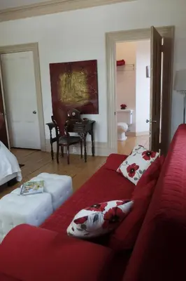 a living room with a red couch and a table at Île de Garde B&B in Sherbrooke