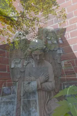a statue of an angel standing next to a brick wall at Île de Garde B&B in Sherbrooke