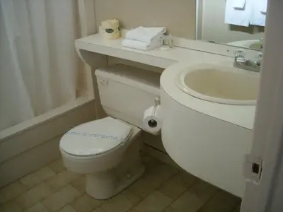 a white bathroom with a toilet and a sink at Grand Motel Saint-Hubert in Longueuil