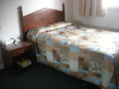 a bedroom with a bed and a night stand with a telephone at Grand Motel Saint-Hubert in Longueuil