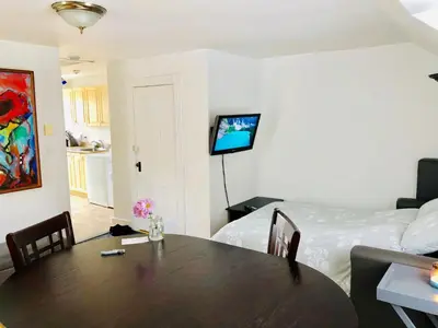 a living room with a table and a bed at L'Appartement de la Suite North Hatley in North Hatley
