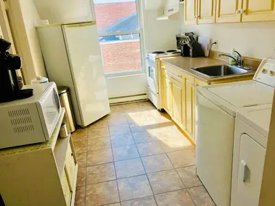 a kitchen with a white refrigerator and a sink at L'Appartement de la Suite North Hatley in North Hatley