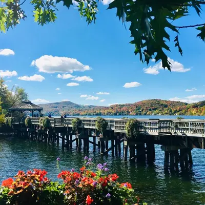 a pier on a lake with flowers in the foreground at L'Appartement de la Suite North Hatley in North Hatley