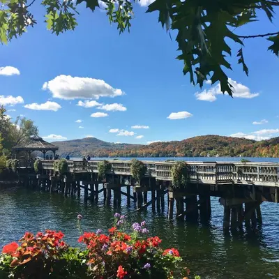 a pier on the water with flowers in the foreground at L'Appartement de la Suite North Hatley in North Hatley