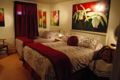 a bedroom with two beds and a painting on the wall at Atelier Galerie Anne Drouin Peinture & Pension in Sainte-Julie