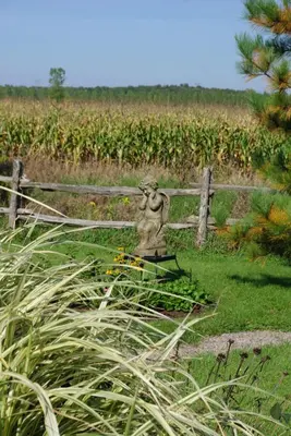 a statue in a field next to a fence at Atelier Galerie Anne Drouin Peinture & Pension in Sainte-Julie