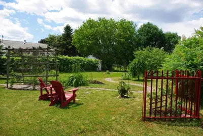 two red benches sitting in the grass near a fence at Atelier Galerie Anne Drouin Peinture & Pension in Sainte-Julie