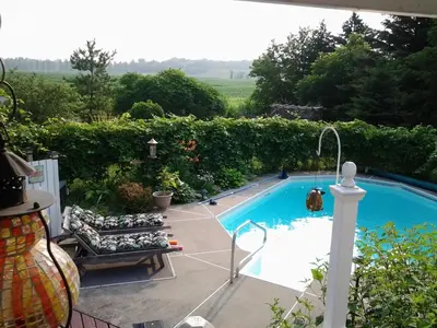a swimming pool with a couch and a chair next to it at Atelier Galerie Anne Drouin Peinture & Pension in Sainte-Julie