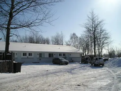 a white building with cars parked in the snow at Motel Le Victo in Victoriaville