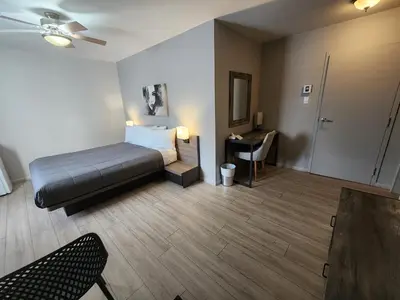 a hotel room with a bed and a desk with a table at Motel Le Victo in Victoriaville