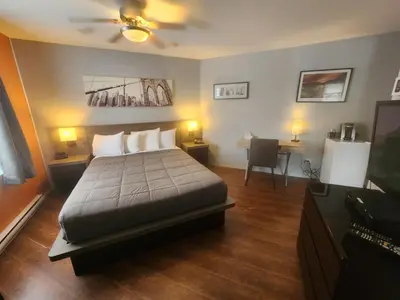 a bedroom with a bed and two tables and two lamps at Motel Le Victo in Victoriaville