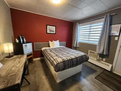a small room with a bed and a window at Motel Le Victo in Victoriaville