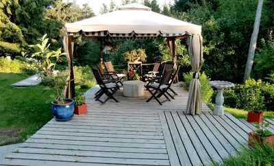 a wooden deck with chairs and a gazebo at Auberge Restaurant La Mara in Saint-Joseph-de-Ham-Sud