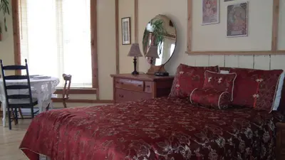 a bedroom with a bed and a table and a mirror at Auberge Restaurant La Mara in Saint-Joseph-de-Ham-Sud