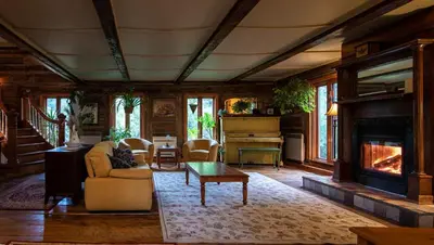 a living room with a fireplace and a piano at Auberge Restaurant La Mara in Saint-Joseph-de-Ham-Sud