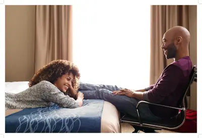 a man sitting next to a girl sitting on a bed at Comfort Inn in Saint-Georges