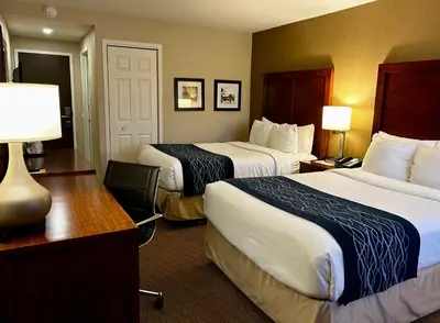 a hotel room with two beds and a desk at Comfort Inn in Saint-Georges