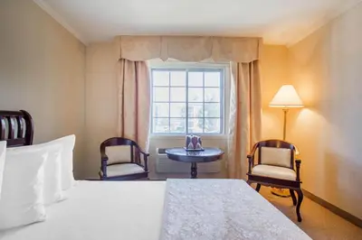 a bedroom with a bed and two chairs and a window at St Christophe Hotel & Spa, an Ascend Collection Hotel in Granby