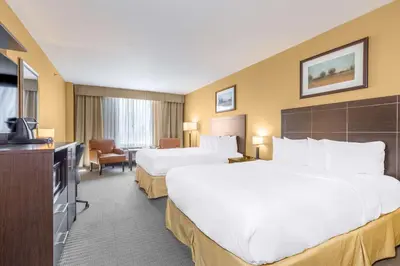 a hotel room with two beds and a flat screen tv at Quality Inn & Suites in Victoriaville