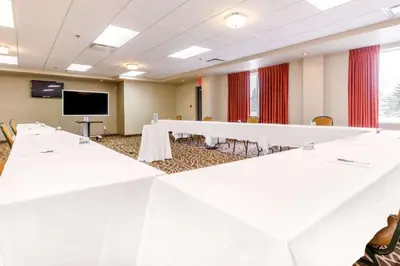 a conference room with white tables and a flat screen tv at Quality Inn & Suites in Victoriaville