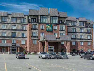 a large building with cars parked in a parking lot at Quality Inn & Suites in Victoriaville