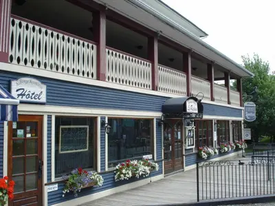 a building with a porch and flowers in front of it at AUBERGE Knowlton in Lac-Brome