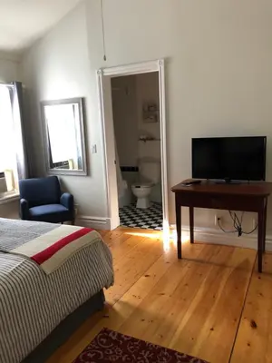 a bedroom with a bed and a desk and a television at AUBERGE Knowlton in Lac-Brome