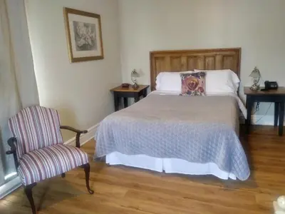 a bedroom with a bed and a chair at AUBERGE Knowlton in Lac-Brome