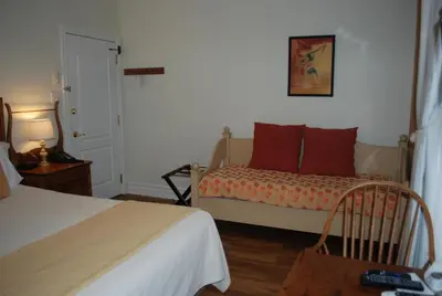 a bedroom with a bed and a chair and a bed at AUBERGE Knowlton in Lac-Brome