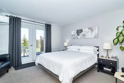 a white bedroom with a bed and a window at Auberge Aux Deux Pères in Magog-Orford