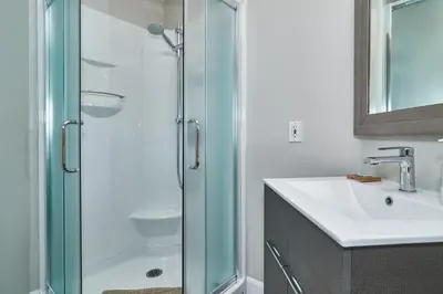a bathroom with a glass shower and a sink at Auberge Aux Deux Pères in Magog-Orford