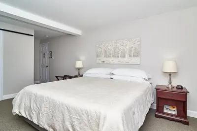 a white bedroom with a white bed and two lamps at Auberge Aux Deux Pères in Magog-Orford