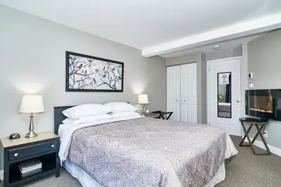 a bedroom with a bed and a flat screen tv at Auberge Aux Deux Pères in Magog-Orford