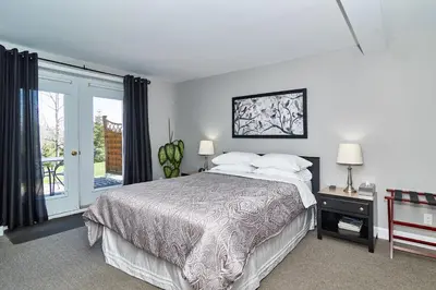 a bedroom with a bed and a sliding glass door at Auberge Aux Deux Pères in Magog-Orford