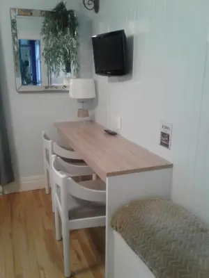 a dining room table with chairs and a television on the wall at Le Gîte Du Coteau in Lyster