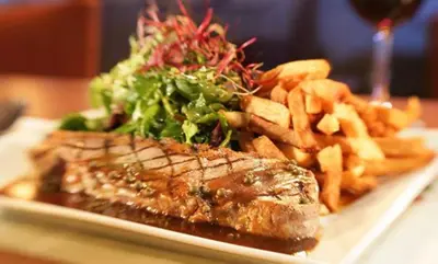 a plate of food with steak and fries and a salad at le Georgesville in Saint-Georges
