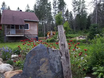a garden with a rock and flowers in front of a house at Domaine de La Giroux-ette in La Patrie
