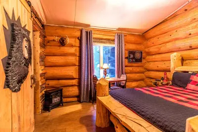 a bedroom with a bed in a log cabin at Domaine de La Giroux-ette in La Patrie