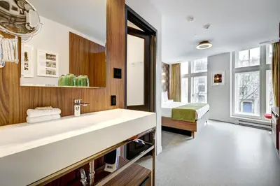 a bathroom with a large white sink and a bed at Hôtel Uville Montréal in Montréal