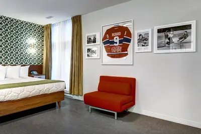 a hotel room with a bed and a red chair at Hôtel Uville Montréal in Montréal